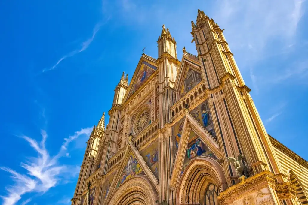 Stunning view of the ornate facade of Duomo di Orvieto Cathedral under a clear blue sky, highlighting its Gothic architecture in Orvieto, Umbria, Italy.