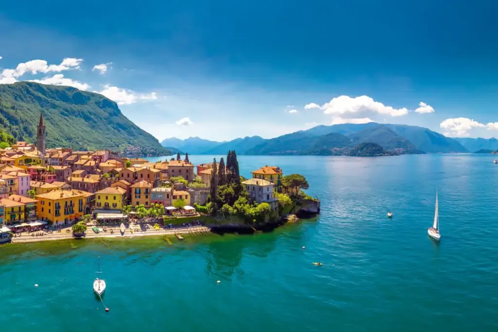 Aerial view of colorful Varenna old town on the shore of Lake Como, with lush green mountains in the background, Italy.