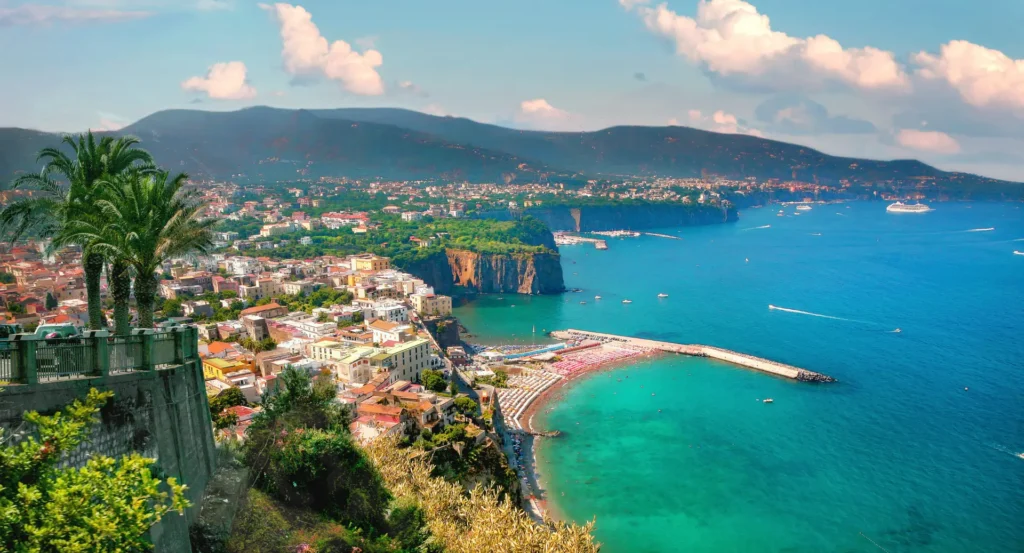Panoramic view of Sorrento town on the Amalfi Coast, Italy, showcasing the vibrant blue waters of the gulf, colorful architecture, and lush greenery.