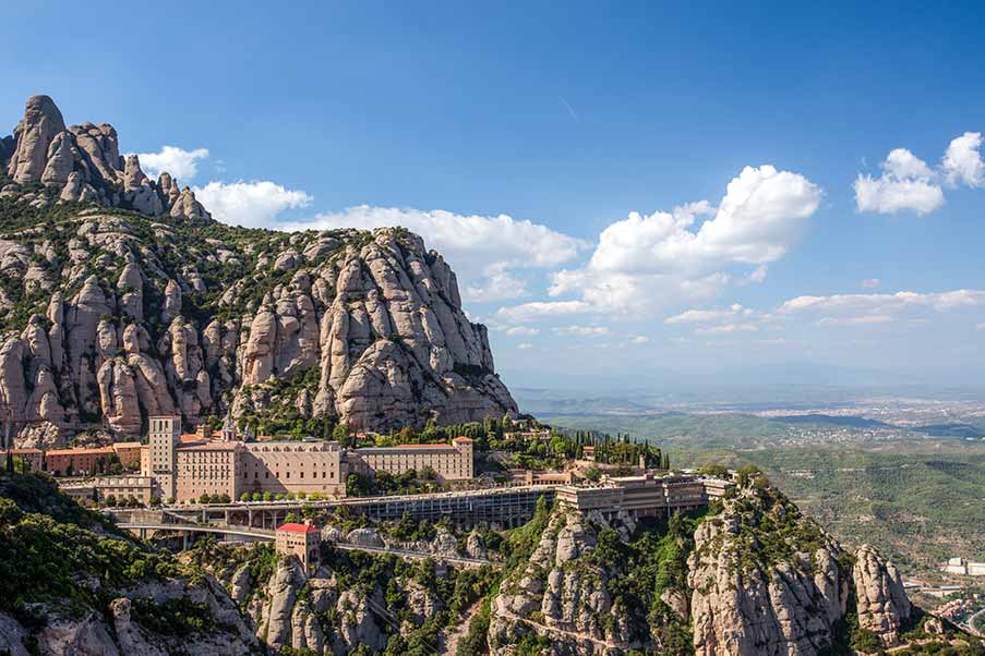Panoramic view of Montserrat Monastery nestled in the rocky mountains of Catalonia, Spain, showcasing its unique architecture and scenic surroundings.