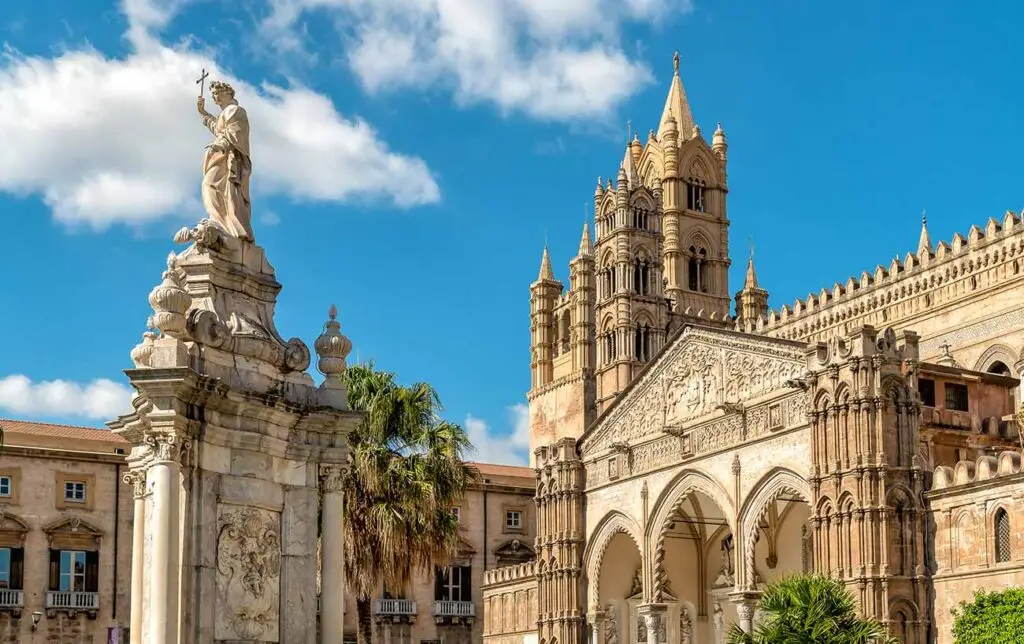 View of Palermo Cathedral and the statue of Santa Rosalia under a blue sky in Sicily, southern Italy, showcasing intricate architectural details and historical significance.