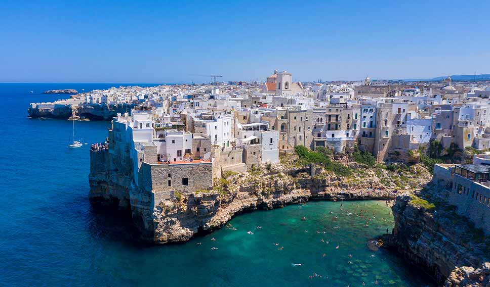 Aerial view of Polignano a Mare, showcasing the stunning cliffside architecture and crystal-clear waters below in Italy.