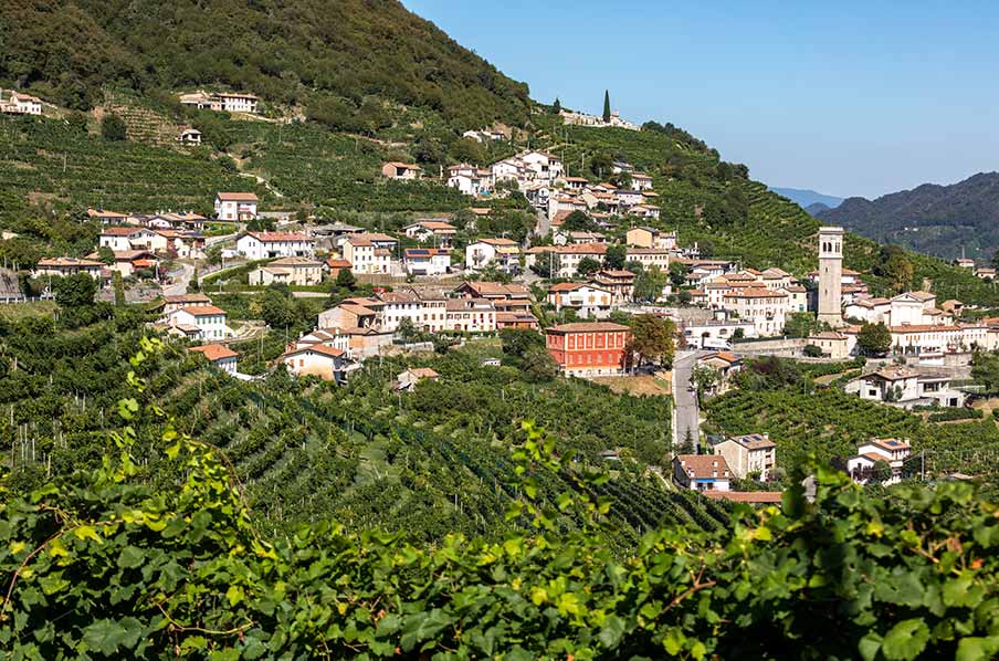 Scenic view of the Prosecco wine region in Veneto, Italy, showcasing lush vineyards and a picturesque village nestled among rolling hills.