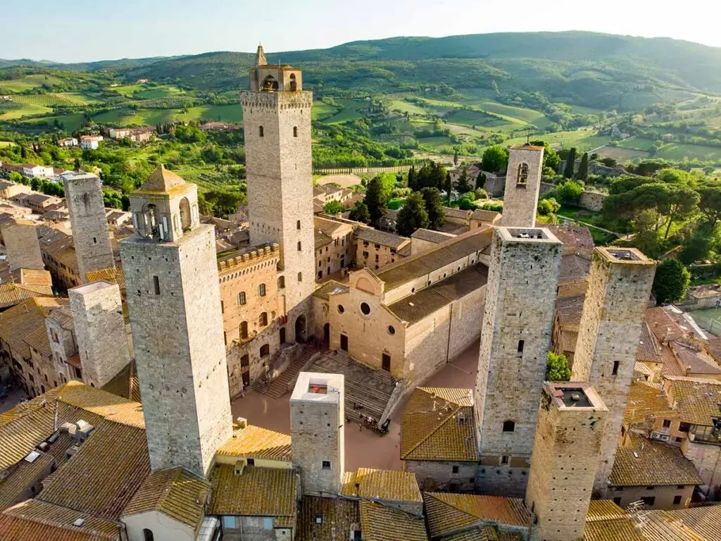 Aerial view of San Gimignano, Italy, showcasing the medieval towers and the lush Tuscan countryside surrounding the historic town.