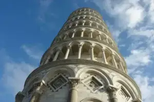 Close-up view of the upper levels of the Leaning Tower of Pisa under a clear blue sky, highlighting the architectural details and craftsmanship of this iconic Italian landmark.