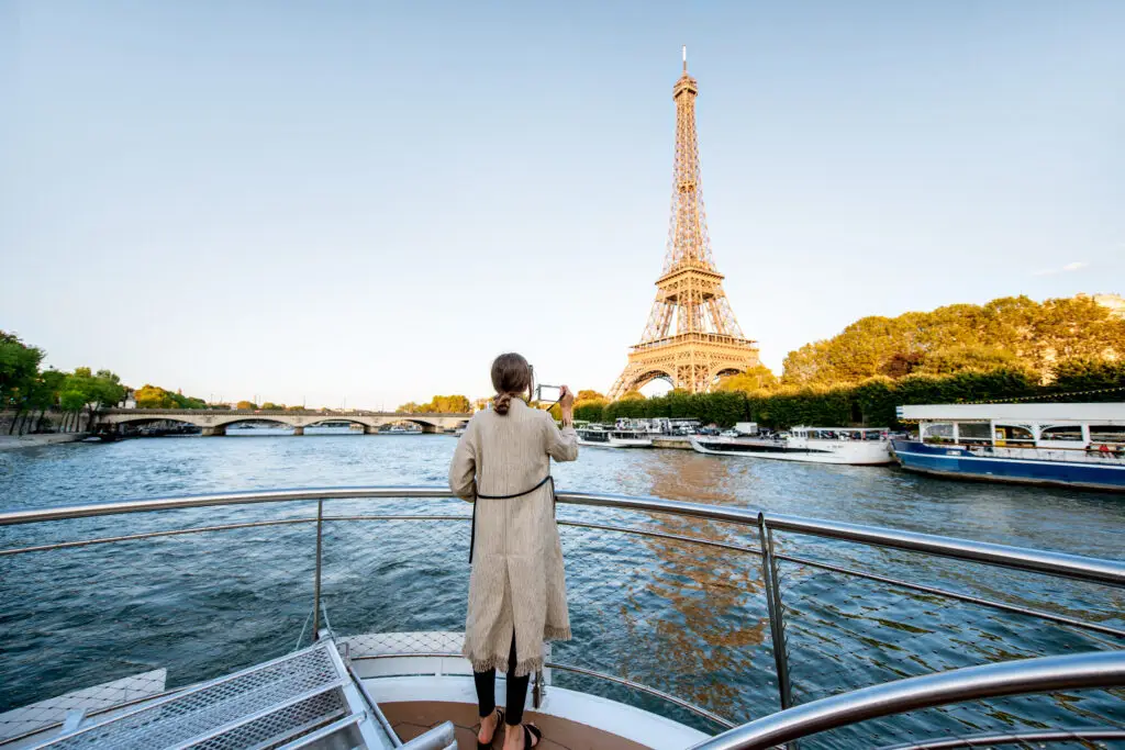 Woman taking photo of the Eiffel Tower from a sightseeing boat on the Seine River in Paris France during a private tour