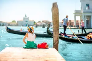 Tourist relaxing by the canal watching gondolas in Venice Italy on a sunny day