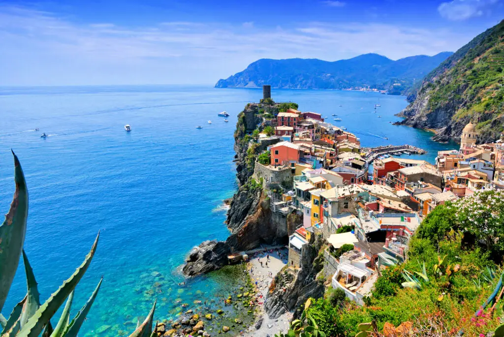 Colorful seaside village of Vernazza in Cinque Terre, Italy, with turquoise waters, boats, and vibrant cliffside houses, a popular travel destination in the Italian Riviera.