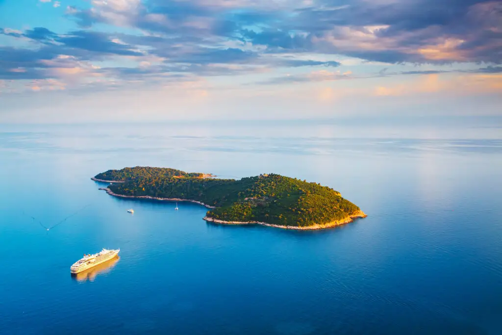 Aerial view of Lokrum Island near Dubrovnik, Croatia, surrounded by turquoise Adriatic Sea with a cruise ship nearby, popular tourist destination for nature and day trips