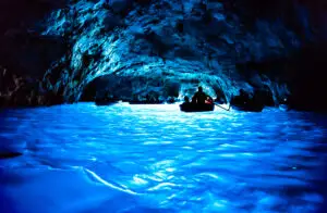 Boats exploring the glowing blue waters inside the Grotta Azzurra sea cave on Capri Island, Italy, a famous European tourist attraction