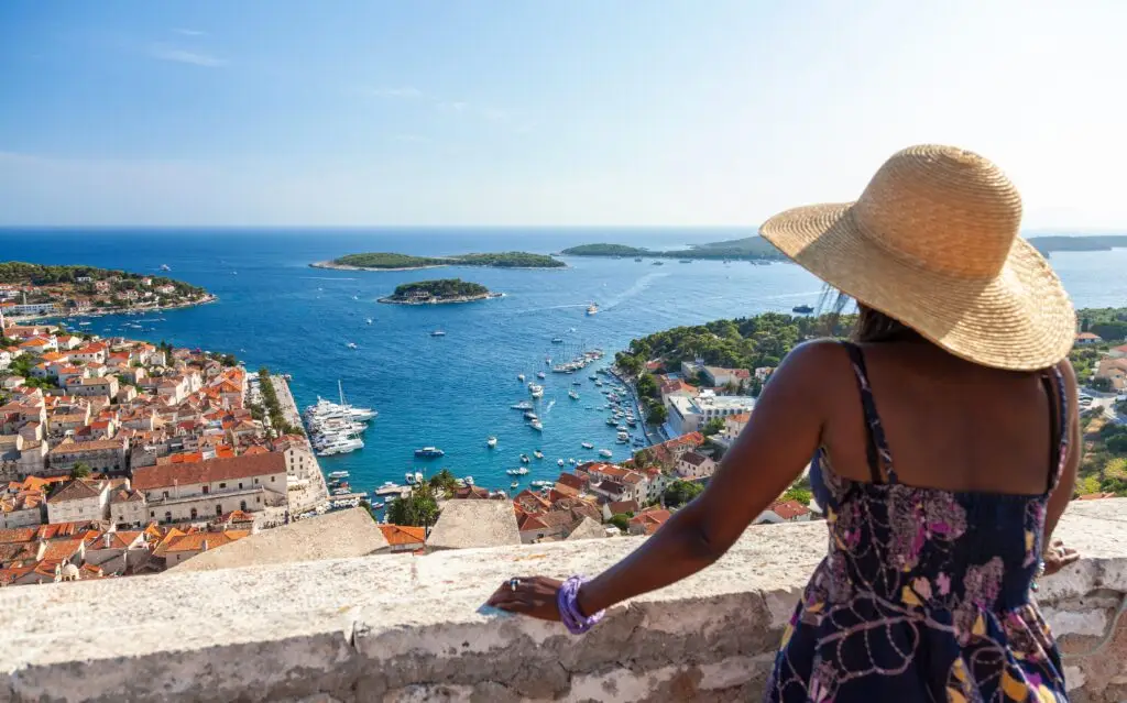 African American woman tourist overlooking Hvar Town and harbor on the island of Hvar, Croatia, enjoying scenic Adriatic Sea view during a European summer vacation