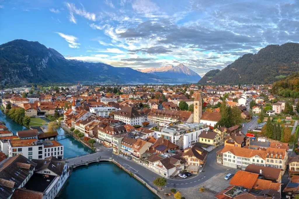Aerial view of Interlaken Switzerland overlooking the Aare River at dusk with traditional Swiss architecture and mountain scenery in the background