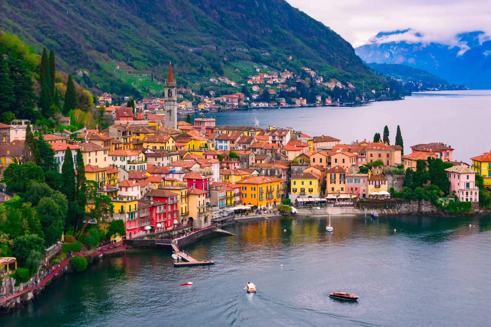 Colorful waterfront village of Varenna on Lake Como, Italy with boats on the water and mountains in the background