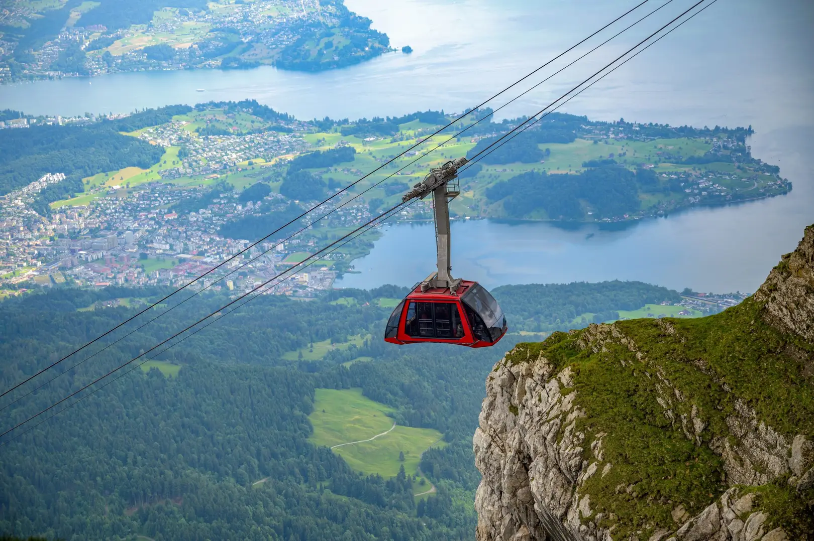 Red cable car ascending Mount Pilatus in Switzerland with panoramic views of Lake Lucerne and the Swiss Alps