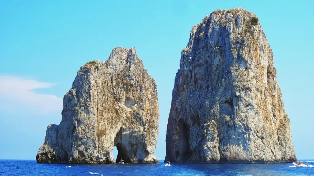 Famous Faraglioni rock formations rising from the blue ocean near Capri Island Italy, a popular Mediterranean tourist attraction and boat tour destination