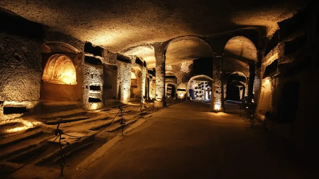 Underground catacombs in Italy with ancient burial niches and arched tunnels lit for guided tours