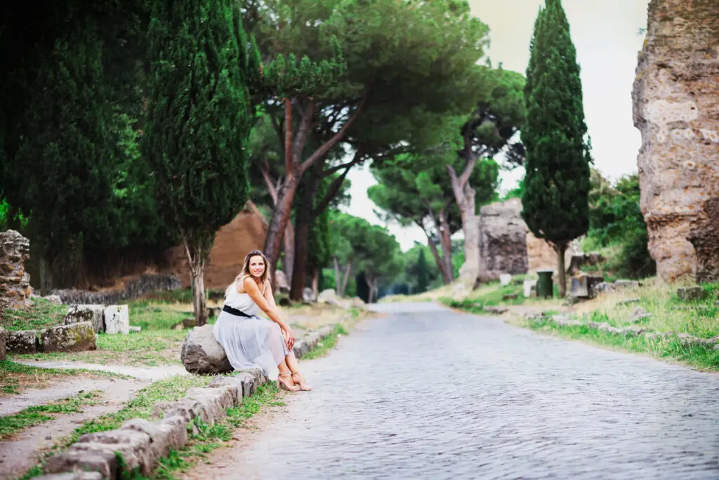 Tourist woman on the ancient Appian Way in Rome, Italy, with cypress trees and Roman ruins
