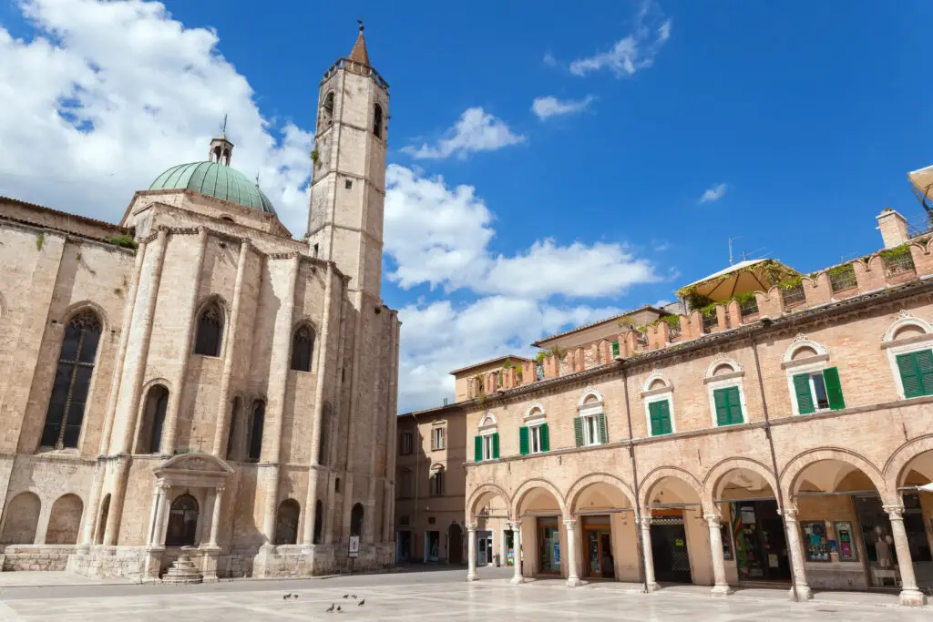 Piazza del Popolo in Ascoli Piceno, Italy, with historic church and arched buildings under a blue sky