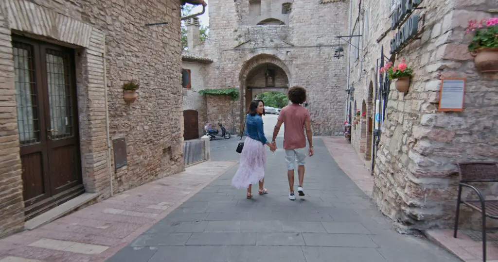 Romantic couple walking through the medieval stone streets of Assisi, Italy on a private Italy tour