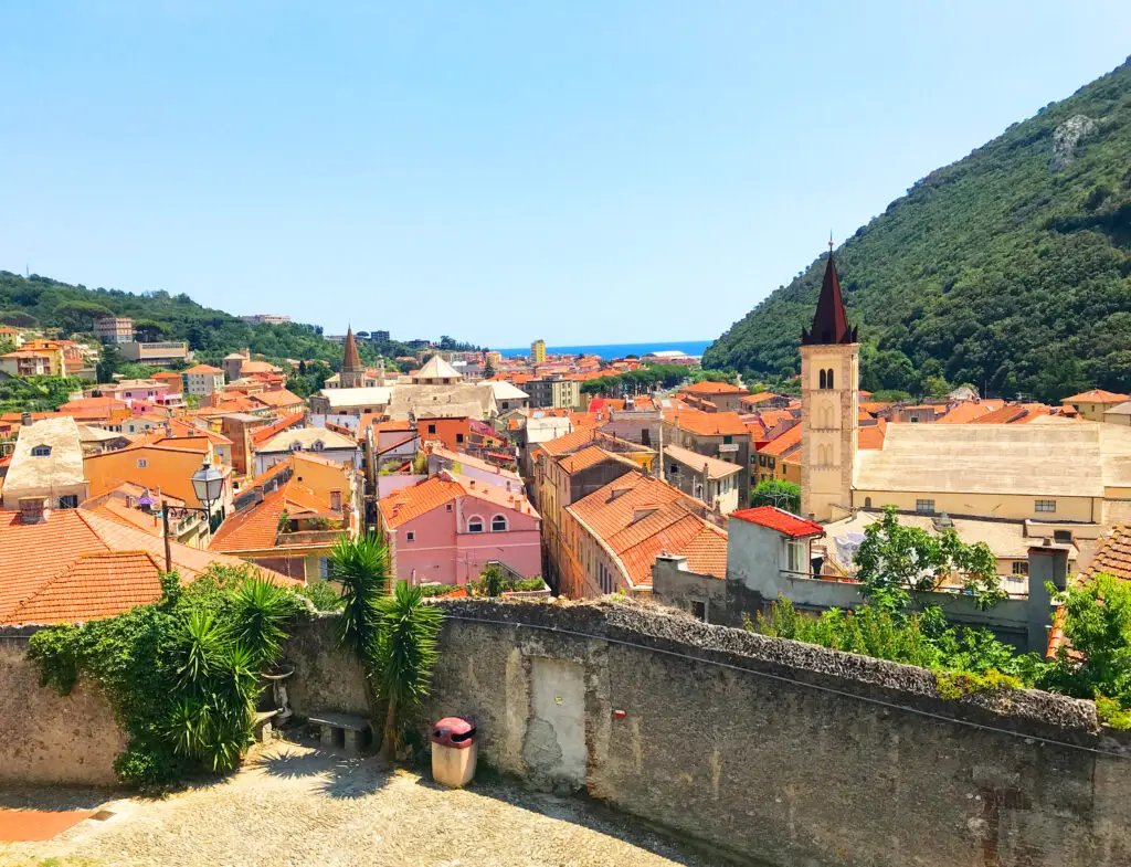 Colorful small town in Liguria Italy with red rooftops, church towers, green hills and Mediterranean sea view