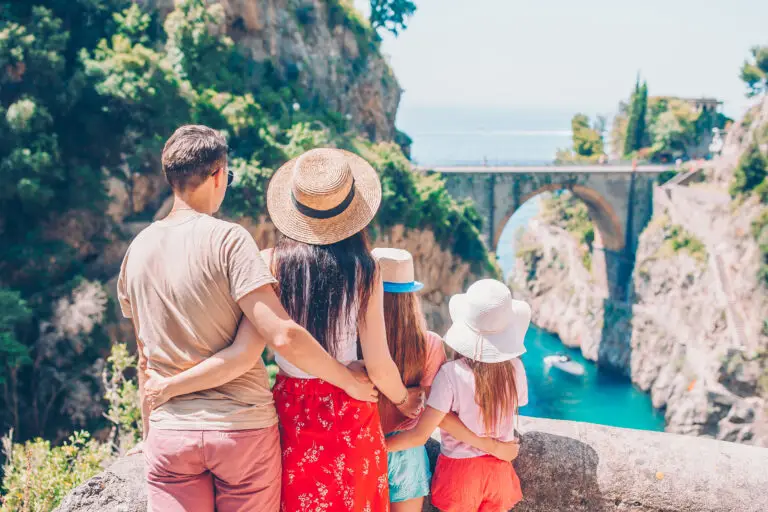 Family enjoying scenic Amalfi Coast view with cliffs, bridge and turquoise sea in Italy