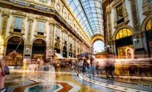 Crowded Galleria Vittorio Emanuele II shopping arcade in Milan, Italy with tourists and luxury boutiques