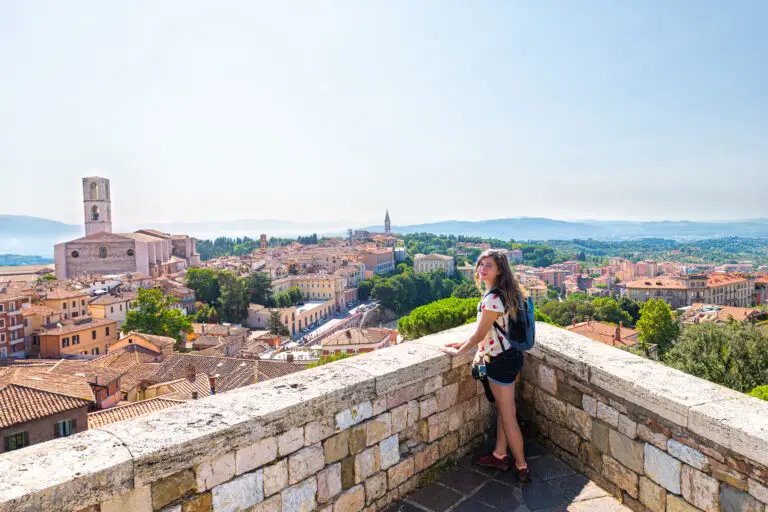 Tourist enjoying panoramic view of Perugia cityscape and historic church in Umbria, Italy
