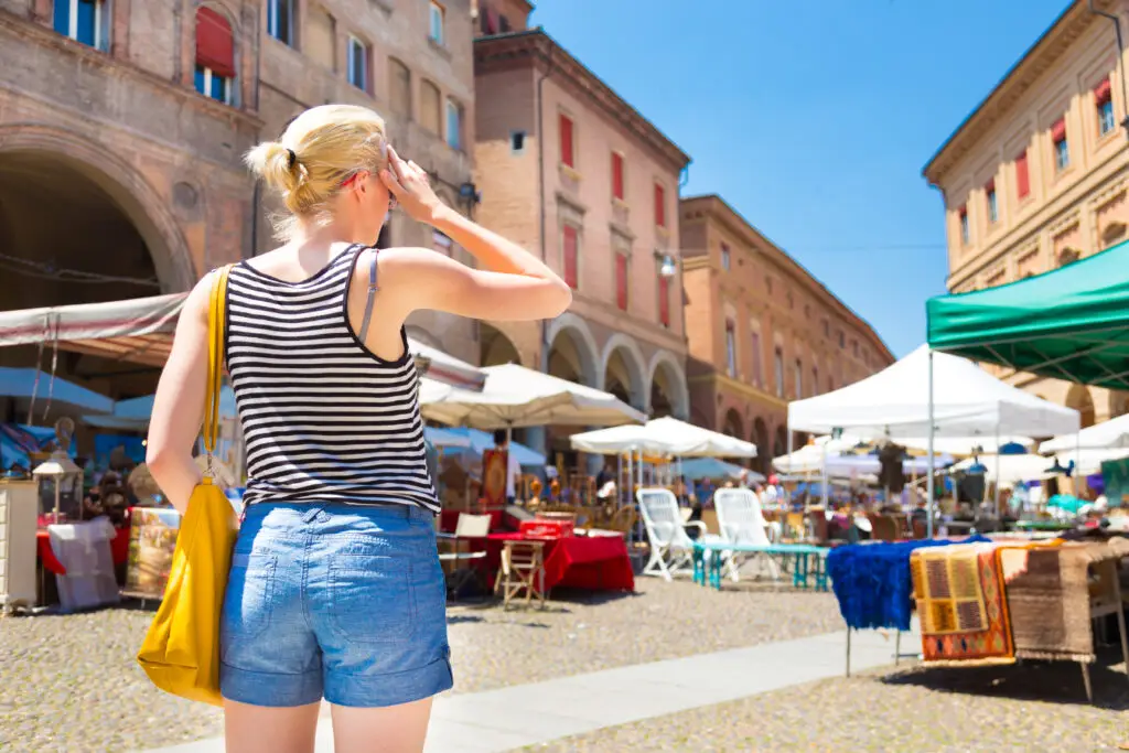 Woman exploring a flea market in a traditional Italian piazza during a private Italy tour