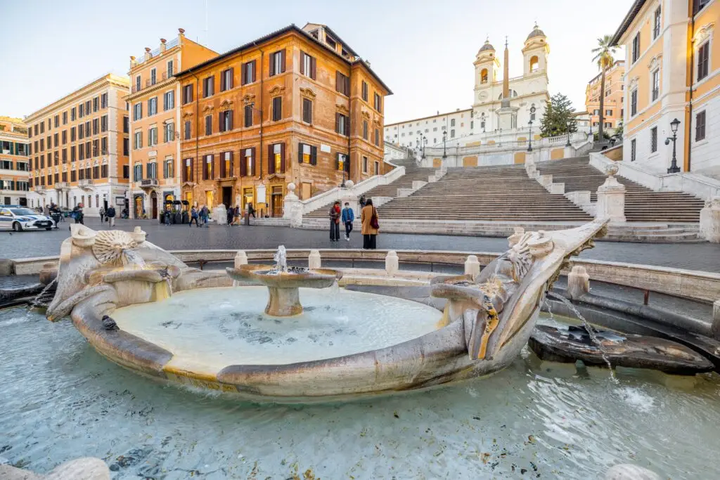 Fontana della Barcaccia fountain and Spanish Steps in Rome, Italy with Trinità dei Monti church in the background