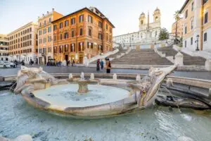Fontana della Barcaccia fountain and Spanish Steps in Rome, Italy with Trinità dei Monti church in the background