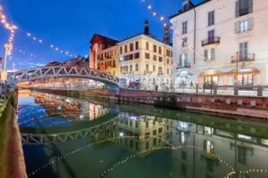 Naviglio Grande canal in Milan, Italy with holiday lights and bridge reflected in the water at twilight