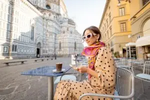 Stylish woman using phone at outdoor cafe near Florence Duomo in Florence, Italy