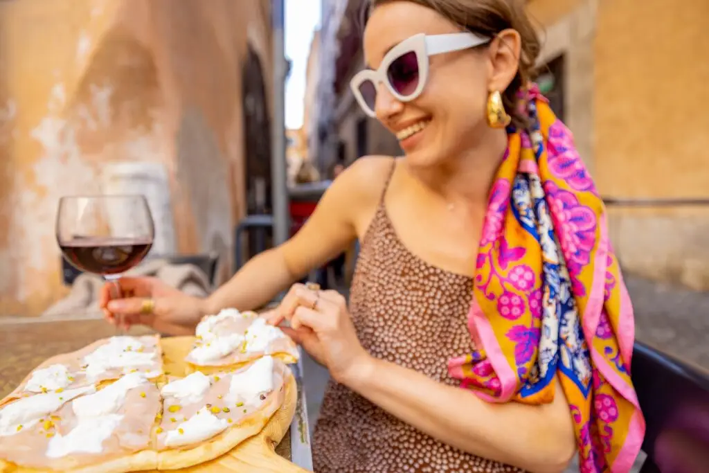 Woman enjoying pizza and red wine at an outdoor restaurant in Italy on a private food tour