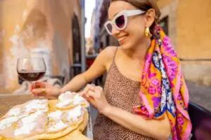 Woman enjoying pizza and red wine at an outdoor restaurant in Italy on a private food tour
