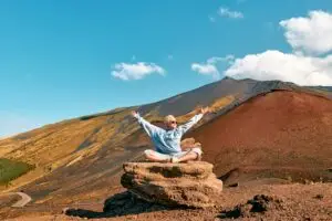 Happy tourist woman doing yoga on Mount Etna volcanic landscape in Sicily, Italy during a private Italy tour