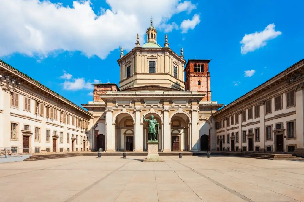 Basilica of San Lorenzo Maggiore Roman Catholic church in Milan, Italy, with courtyard and statue under blue sky