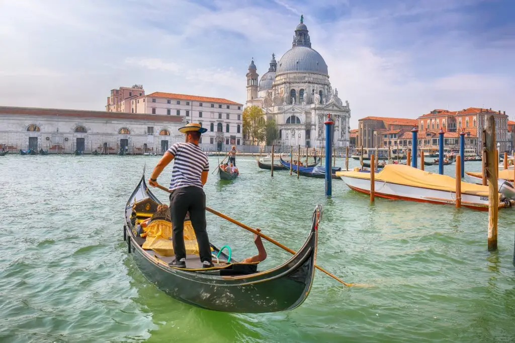 Gondola ride on the Grand Canal in Venice, Italy, with Basilica di Santa Maria della Salute in the morning cityscape