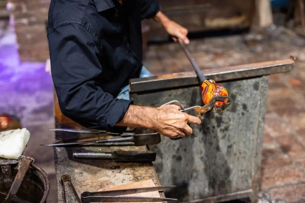 Glass blower shaping colorful molten glass in a Murano workshop in Italy