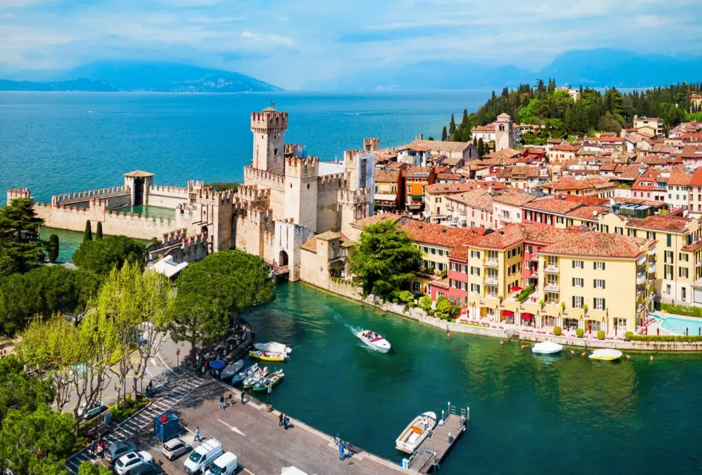 Aerial panoramic view of Scaligero Castle in Sirmione on Lake Garda, Italy, with historic town rooftops and turquoise water