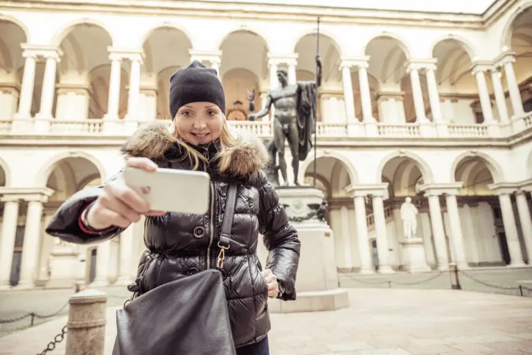 Young tourist taking a selfie in the Brera Art Gallery courtyard in Milan, Italy
