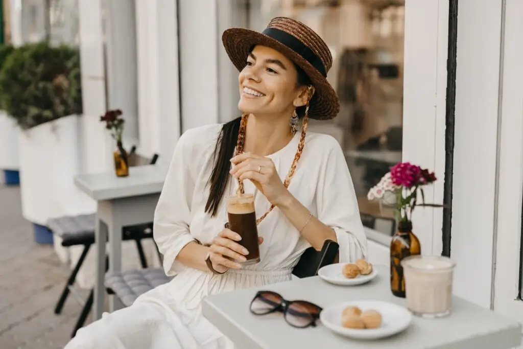 Woman in white dress enjoying coffee at an outdoor cafe during an Italy vacation