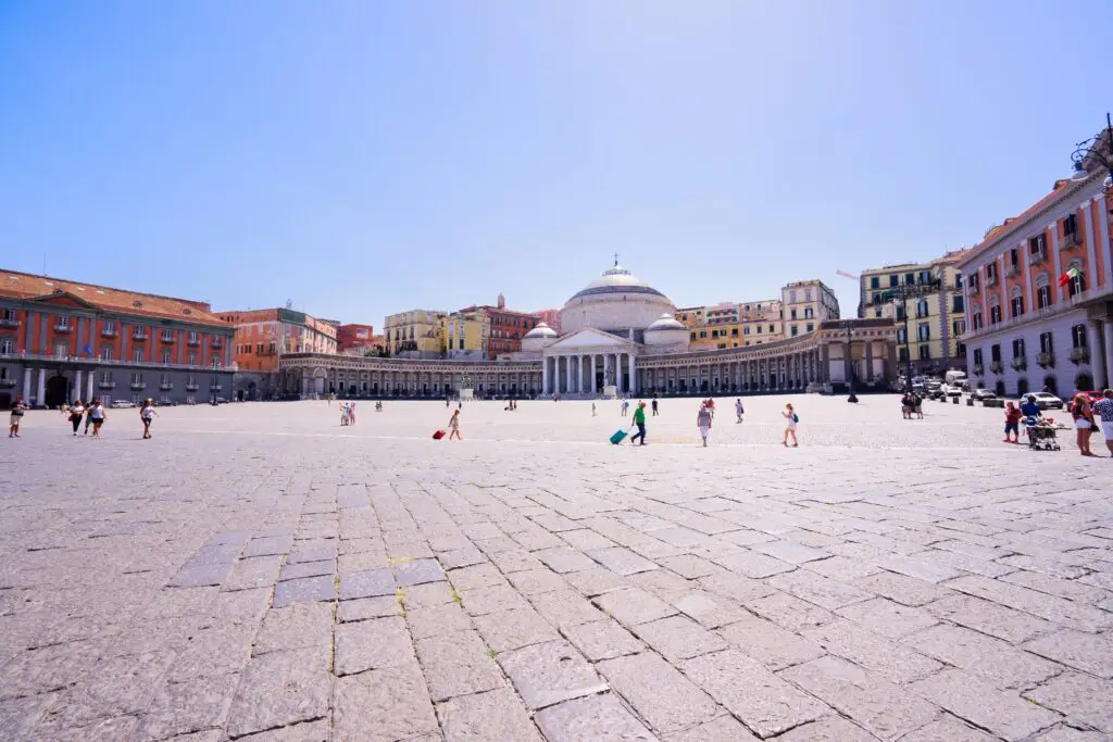 Piazza del Plebiscito in Naples, Italy, with Basilica of San Francesco di Paola and historic city buildings under a clear blue sky