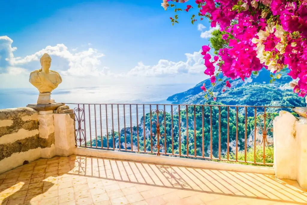 Ravello terrace with ancient sculpture, bougainvillea, and panoramic sea view over the Amalfi Coast in Italy