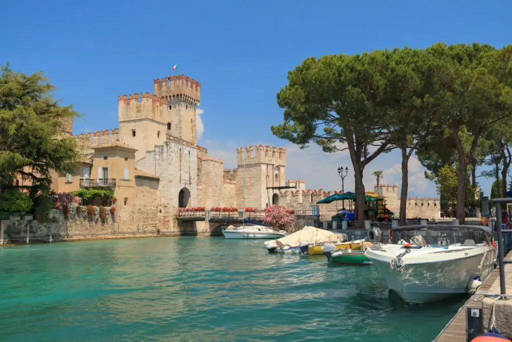 Scaliger Castle of Sirmione on Lake Garda, Italy, with boats in turquoise water on a sunny day