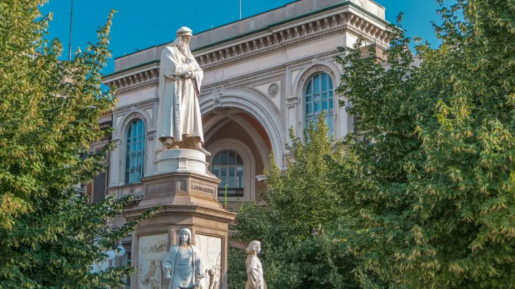 Monument to Leonardo da Vinci in Piazza della Scala, Milan, Italy, with historic architecture and trees in the square