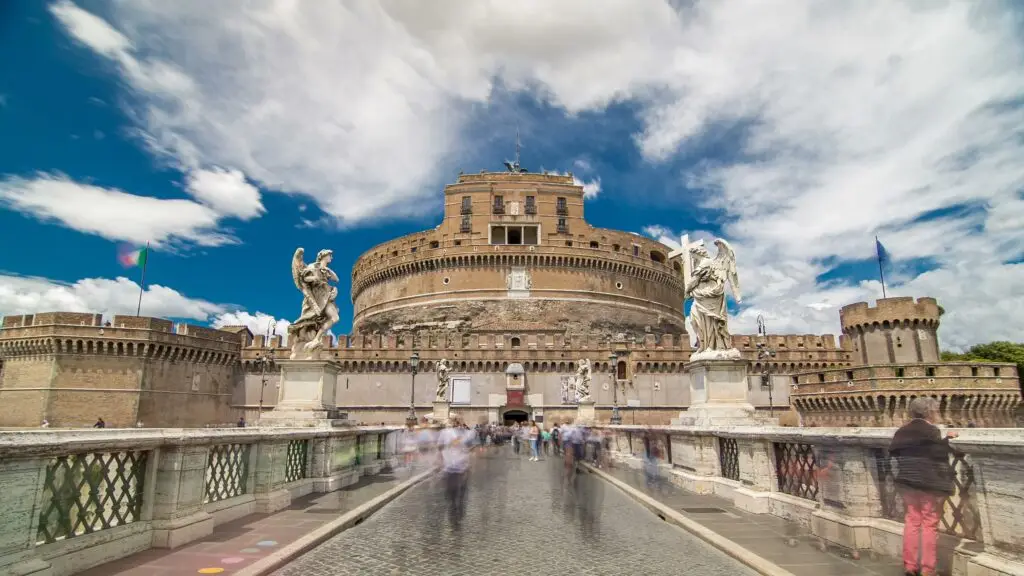 Castel Sant’Angelo in Rome, Italy, viewed from Ponte Sant’Angelo with angel statues and tourists under a dramatic sky