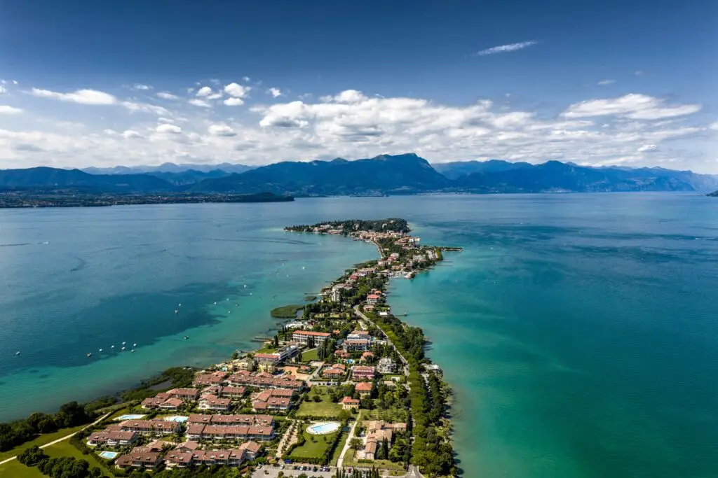 Aerial view of Sirmione Peninsula on Lake Garda in Italy with turquoise water, lakeside town, and mountain scenery