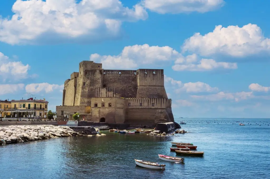 Castel dell’Ovo Egg Castle on the Naples waterfront in Italy with boats in the Bay of Naples under a blue sky