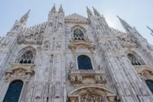 Duomo di Milano Gothic cathedral facade in Milan, Italy, with ornate spires, statues, and marble architecture in Piazza del Duomo