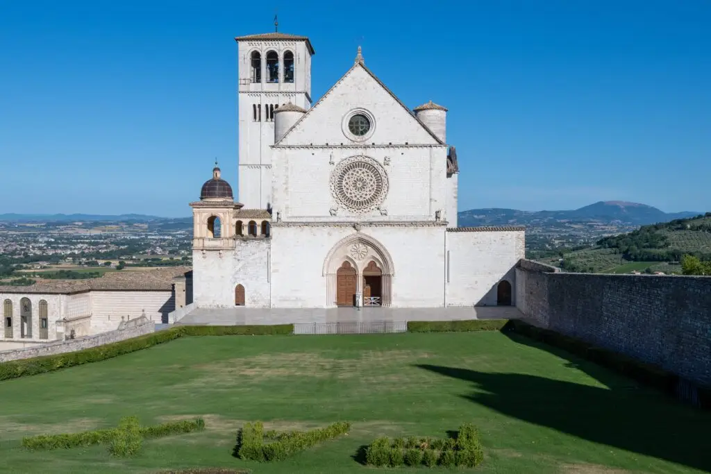 13th-century Papal Basilica of Saint Francis in Assisi, Italy with white stone facade and Umbrian countryside views